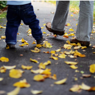Pieds d'un adulte et d'un enfant marchant sur des feuilles