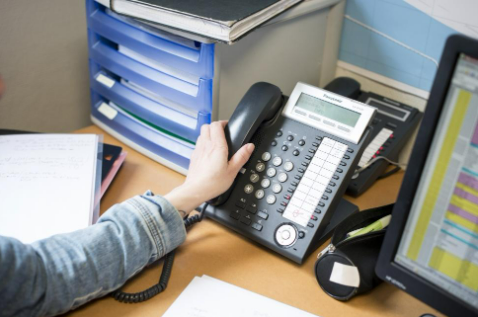 Main décrochant un téléphone de bureau